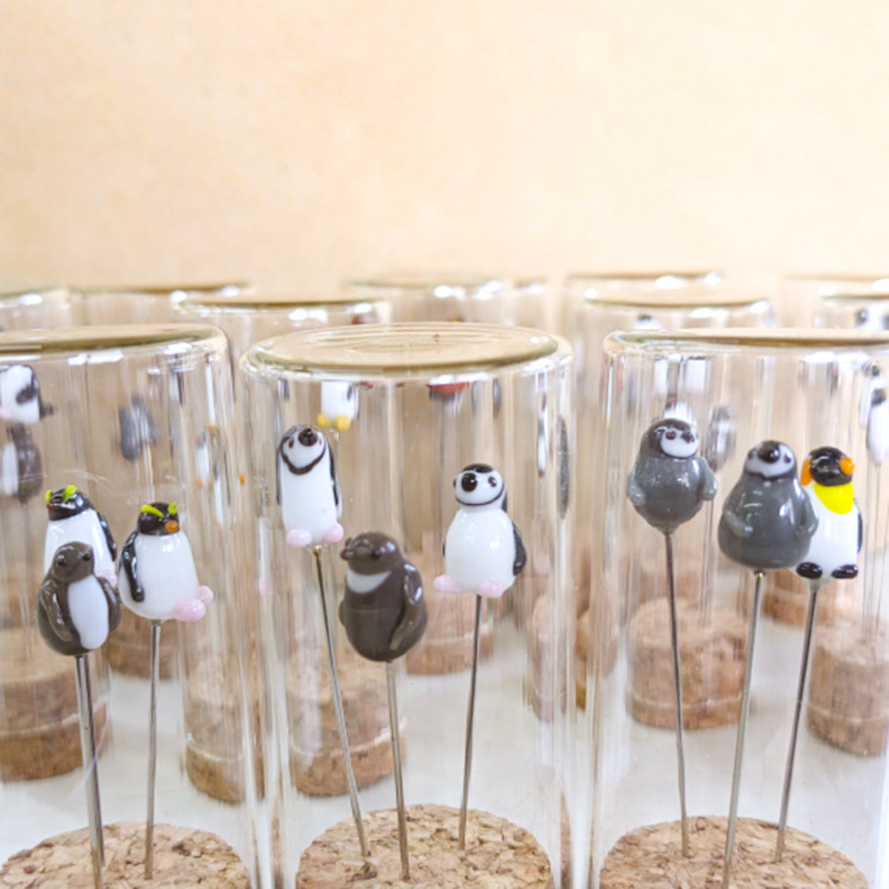 10ミリほどのちいさなガラスのペンギンをまち針に仕立てて瓶にセットしています。